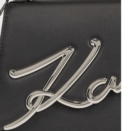 Gros plan de la signature Karl métallique argentée en relief sur le cuir noir du petit sac bandoulière Karl Lagerfeld K/Signature