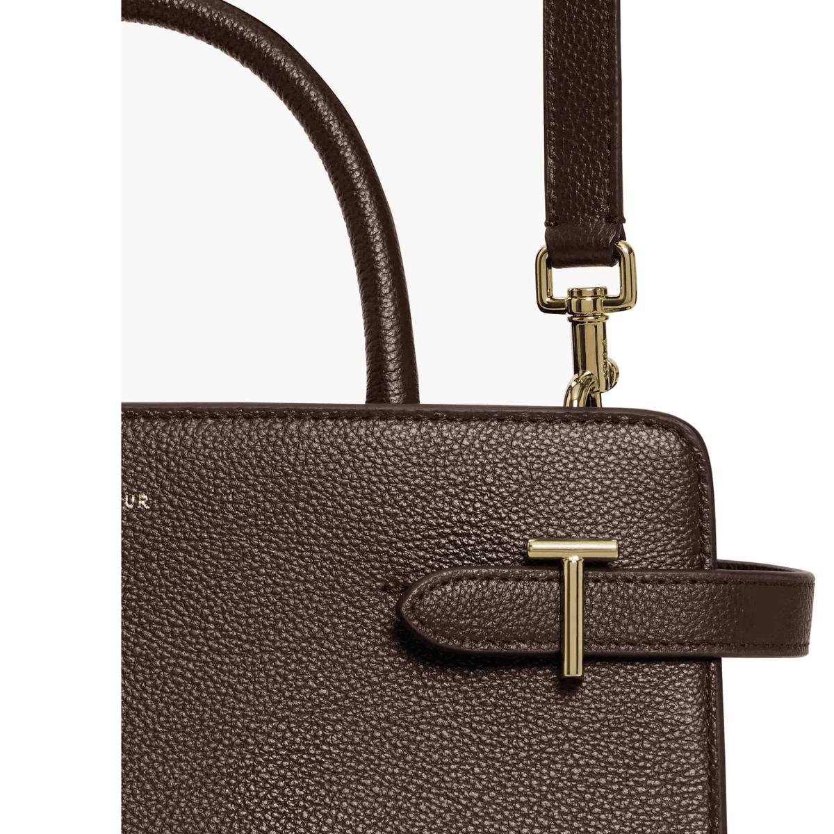 Gros plan du cuir grainé marron foncé du sac Émilie moyen modèle Le Tanneur, détail du T doré et mousqueton de bandoulière