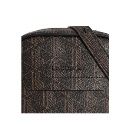 Gros plan sur le monogramme grainé et le logo Lacoste de la sacoche The Blend marron.