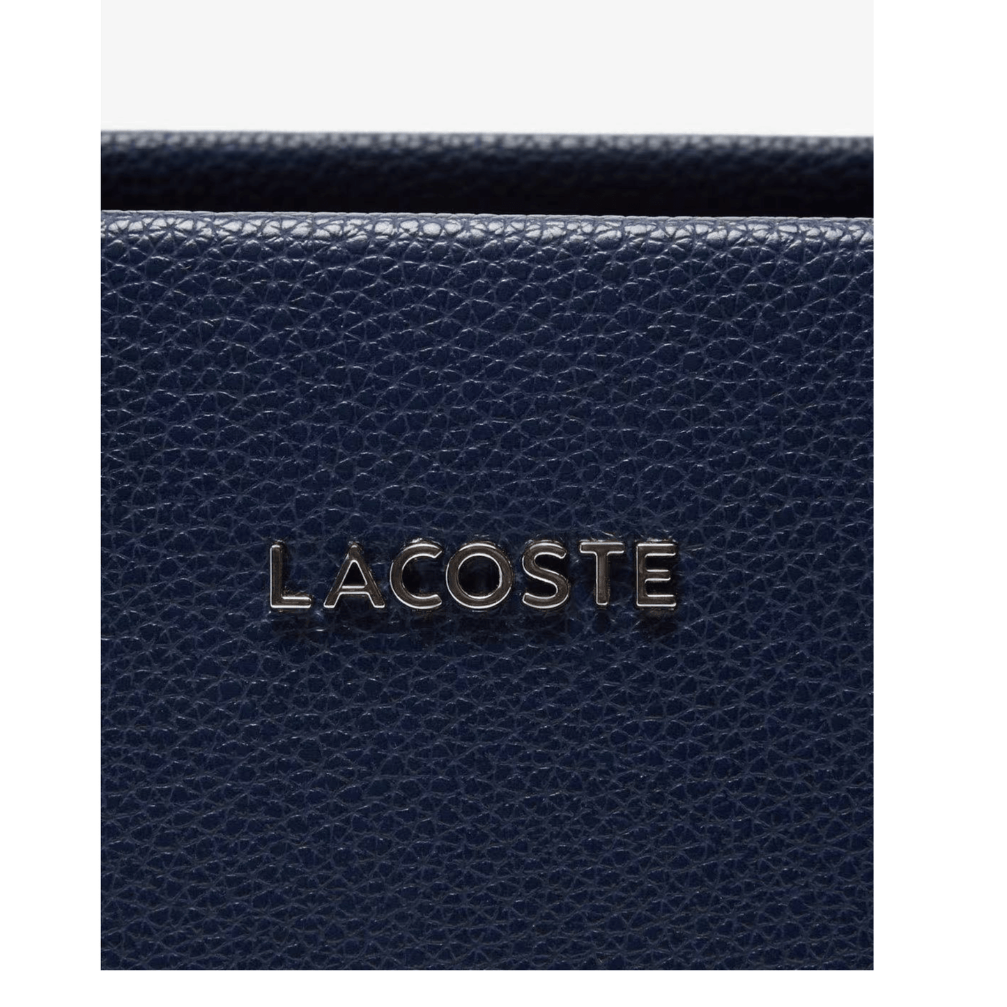 Détail logo Lacoste métallique sur sac bleu marine