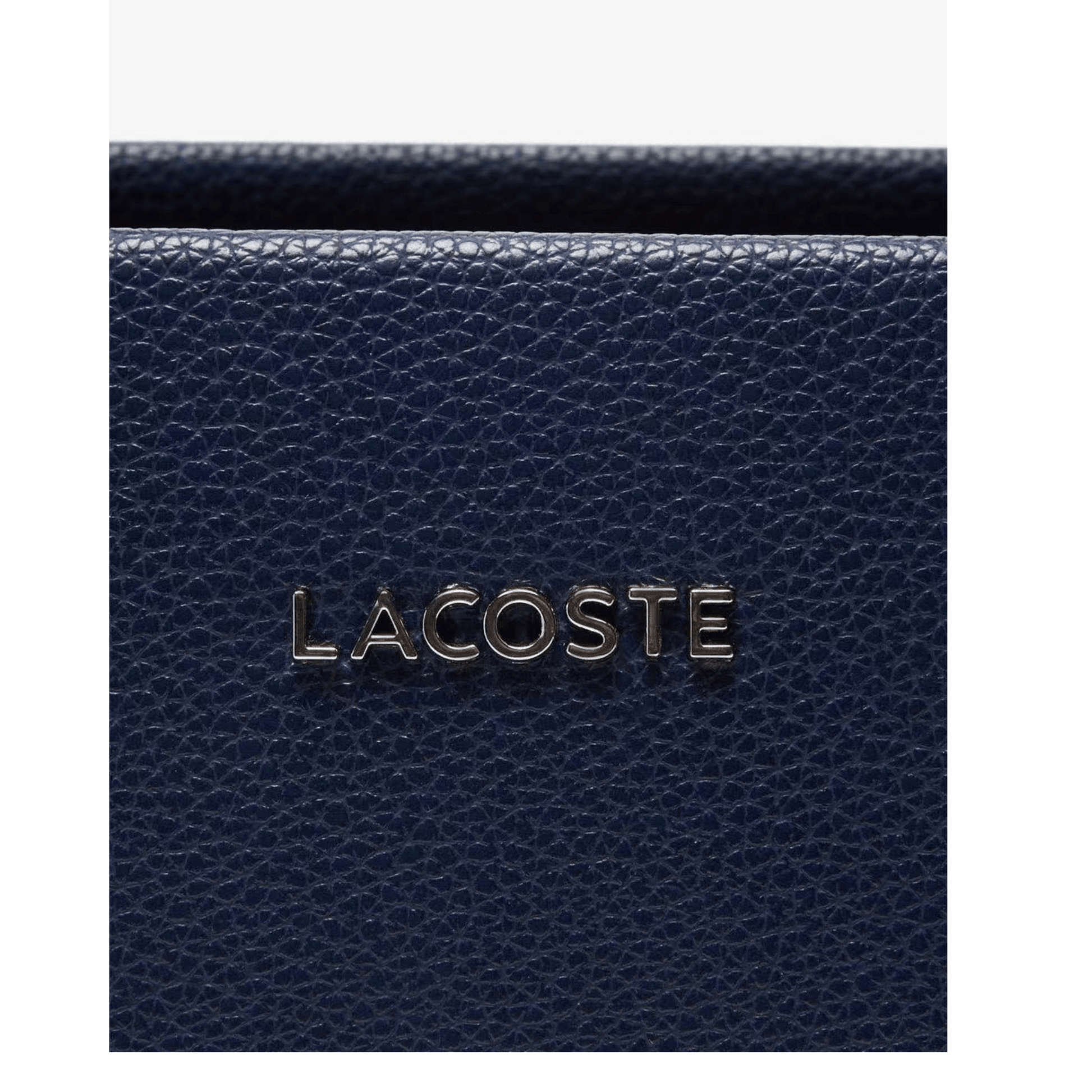 Détail logo Lacoste métallique sur sac bleu marine