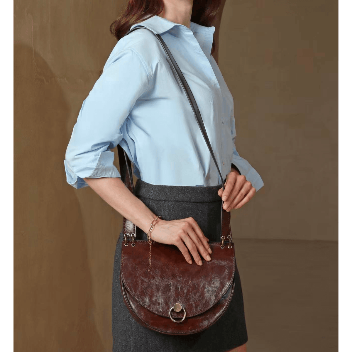 Sac bandoulière marron Inès Delaure porté par une femme avec tenue élégante