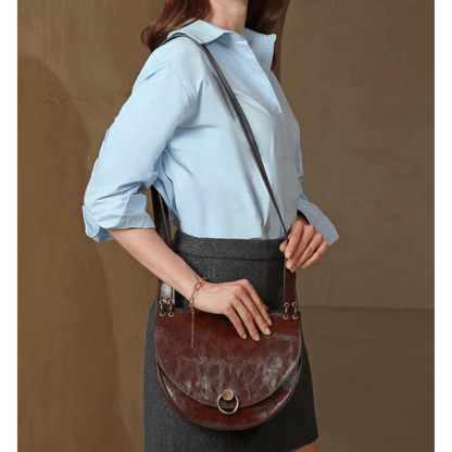 Sac bandoulière marron Inès Delaure porté par une femme avec tenue élégante
