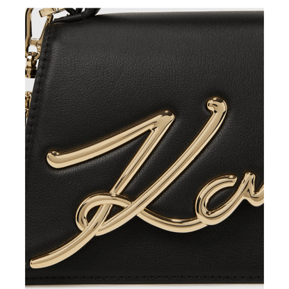 Gros plan de la signature Karl métallique dorée sur le cuir noir du sac bandoulière Karl Lagerfeld K/Signature
