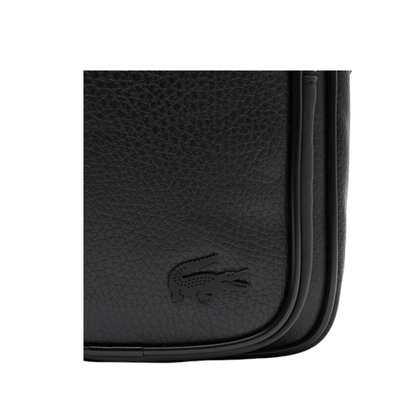 Gros plan sur le logo crocodile Lacoste ton sur ton et la finition grainée du sac reporter homme noir NH4783GY00
