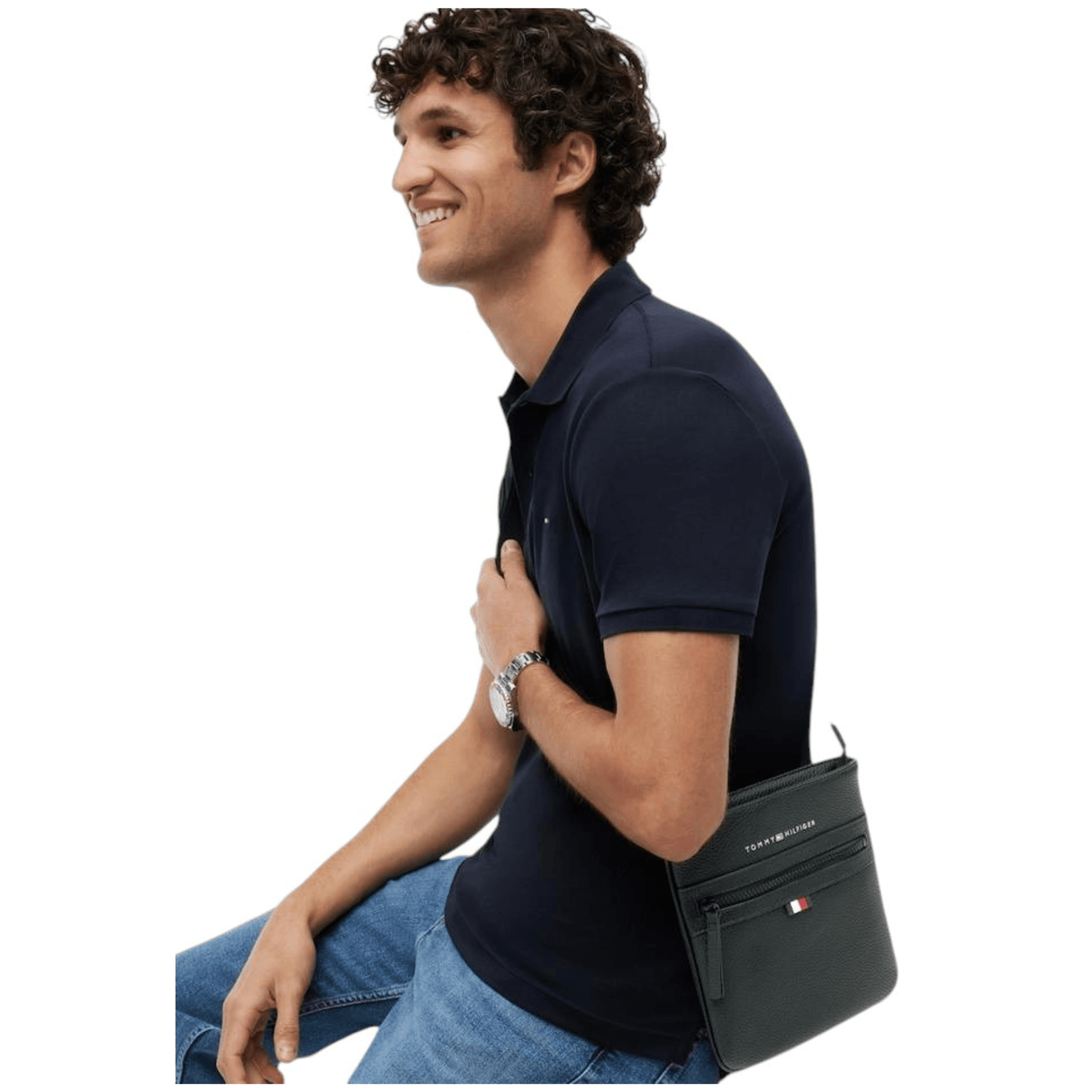 Homme portant la sacoche plate noire Tommy Hilfiger AM0AM09505 en bandoulière avec polo bleu marine
